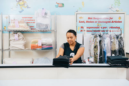 laundromat attendant folding polo shirts for a fluff and fold order