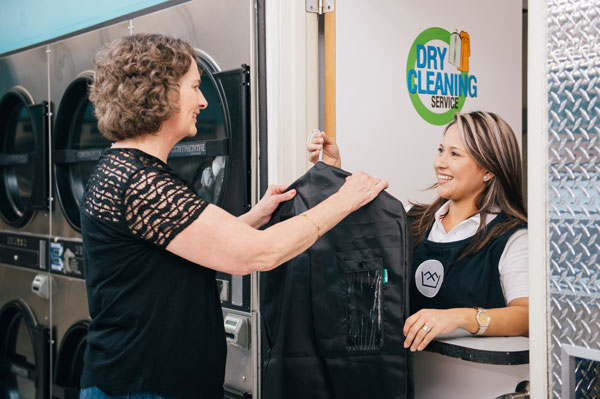 Customer picking up her dry cleaning order from the laundromat attendant
